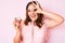 Young beautiful caucasian woman holding cupcake smiling happy doing ok sign with hand on eye looking through fingers