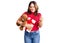 Young beautiful caucasian woman holding gift and teddy bear annoyed and frustrated shouting with anger, yelling crazy with anger