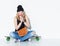 Young beautiful cheerful fashion girl in jeans, sneakers, hat sitting on a longboard with a vintage bag on her shoulder and eat