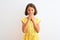 Young beautiful child girl wearing yellow floral dress standing over isolated white background laughing and embarrassed giggle