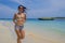 Young beautiful Chinese Asian girl in shorts and bikini running on beach sand with amazing beautiful turquoise sea water color en