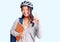 Young beautiful chinese girl wearing student backpack and bike helmet holding book surprised with an idea or question pointing