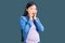 Young beautiful chinese woman pregnant expecting baby afraid and shocked, surprise and amazed expression with hands on face