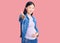 Young beautiful chinese woman pregnant expecting baby smiling friendly offering handshake as greeting and welcoming