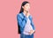 Young beautiful chinese woman pregnant expecting baby thinking concentrated about doubt with finger on chin and looking up