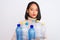 Young beautiful chinese woman recycling plastic bottles over isolated white background with a confident expression on smart face