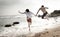 Young beautiful couple having fun jumping along beach