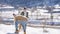 Young beautiful couple having fun with small active dog on a snowy hill