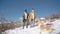 Young beautiful couple having fun with small active dog on a snowy hill