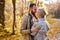 young and beautiful couple hugging with love in the middle of park during autumn.