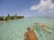 Young beautiful couple lying and floating on back in turquoise sea water on tropical paradise beach in Bora Bora Island, French