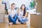 Young beautiful couple sitting on the floor at new home around cardboard boxes with hand on chin thinking about question, pensive