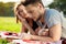 Young beautiful couple smiling, reading, resting on picnic in park.