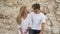 Young beautiful couple stand near big rocks and talking