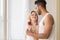 Young Beautiful Couple Stand Near Big Window, Hispanic Man Give Woman Red Rose