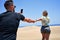 Young beautiful couple,  standing backwards making photo at the beach