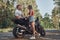 Young beautiful couple talking and having fun, sitting on a motorcycle, traveling together on a forest road