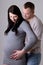 Young beautiful couple waiting baby over grey