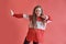 Young beautiful cute girl dancing on red background, modern slim hip-hop style teenage girl jumping