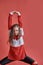 Young beautiful cute girl dancing on red background, modern slim hip-hop style teenage girl jumping