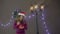 Young beautiful cute girl smiling wearing Santa hat, holding lantern in hand on background of Christmas decorations