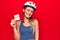 Young beautiful cyclist woman wearing bike security helmet holding reminder with help message looking positive and happy standing