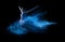 Young beautiful dancer jumping into blue powder cloud