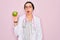 Young beautiful doctor woman with blue eyes wearing stethoscope holding green apple fruit scared in shock with a surprise face,