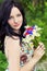 Young beautiful elegant girl, blue eyes with long black hair standing in the garden a bouquet of daisies poppies