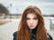 Young beautiful emotional redhead woman in stylish trench coat, big plaid scarf enjoying vacations free time on a background of