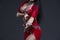 Young beautiful exotic eastern women performs belly dance in ethnic red dress on gray background