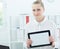 Young beautiful famale secretary holding tablet in hands sitting at office. Tablet with empty space for advertising.