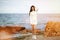 Young beautiful fashion woman standing on the autumn beach. Happy outdoor fall lifestyle. Vacation. Ocean beach relax. Stylish