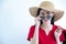 Young beautiful fashionable Asian woman holding shopping bags wearing red dress, sunglasses and hat over white background studio