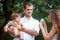 Young beautiful father, mother and little toddler son against green trees