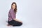 Young beautiful female with dark brown hair and eyes sits on the floor on her knees, the wrench in the back pocket of black jeans.