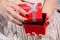 Young Beautiful Female Hands Opening Red Gift Box on Woolen Sweater Background