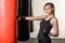 Young, beautiful and fit blond lady is working out in a loft gym. She is wearing black sport tank top and boxing gloves.