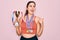 Young beautiful fitness winner athlete woman wearing sport medals and trophy pointing and showing with thumb up to the side with