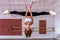 Young beautiful flexible girl in white crop top and black leggings hangs upside down in the splits. Stretching and body ballet