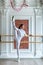 Young beautiful flexible girl in white jumpsuit is posing in a dance studio. Stretching and body ballet theme. Modern dance trend