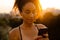 Young beautiful focused curly african woman holding and using phone