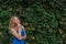 Young beautiful girl on a background of a wall of wild grapes, ponders, thinks an idea. Copy space