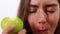 Young beautiful girl bites a green apple.