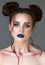 Young beautiful girl with the colorfull make-up, bunches hairstyle, blue lips and eyearrows