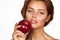 Young beautiful girl with dark curly hair, bare shoulders and neck, holding big red apple to enjoy the taste and are dieting,