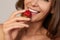 Young beautiful girl with dark curly hair, bare shoulders and neck, holding strawberry to enjoy the taste and are dieting,