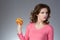 Young beautiful girl disdainfully holding a junk food from fast
