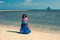 Young beautiful girl in a dress stands on the white sand by the sea at low tide.