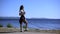 Young beautiful girl drinking water from a bottle in the summer against the sea